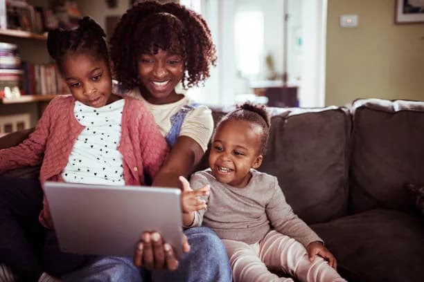 A family at home sharing a tablet on the sofa
